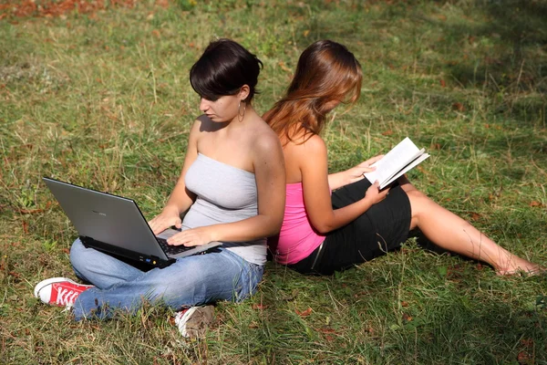 Chicas con portátil y libro Imagen de archivo