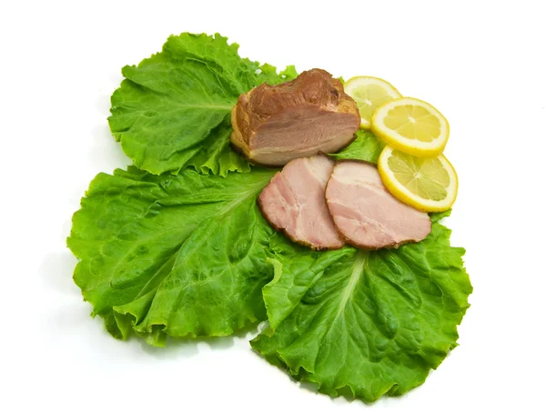 stock image Sliced ham on leaves of salad with a lem