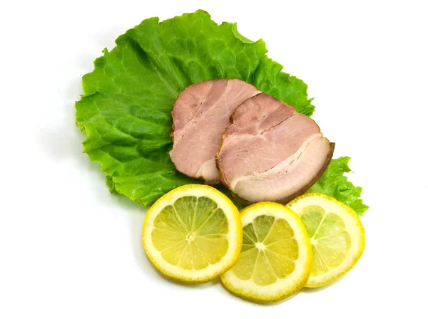 Stock image Sliced ham on leaves of salad with a lem