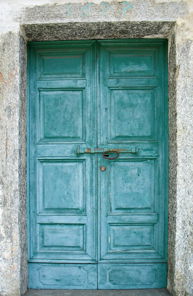 An old green door of a church in a mountain village, Italy