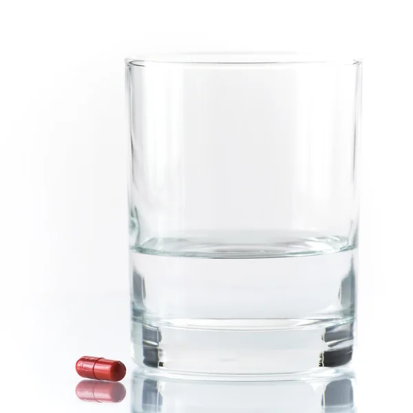 Primo piano di pillola rossa e acqua — Foto Stock