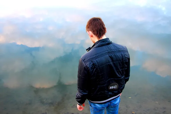 Junger Mann in schwarzer Jacke auf dem Fluss — Stockfoto