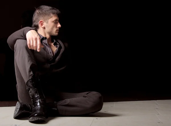 Stilvoller junger Mann sitzt auf einem Fußboden — Stockfoto