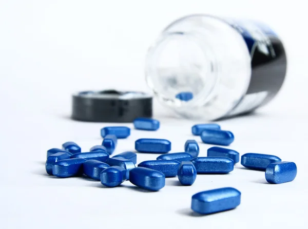 Blaue Pillen aus Tablettenflasche geschüttet — Stockfoto