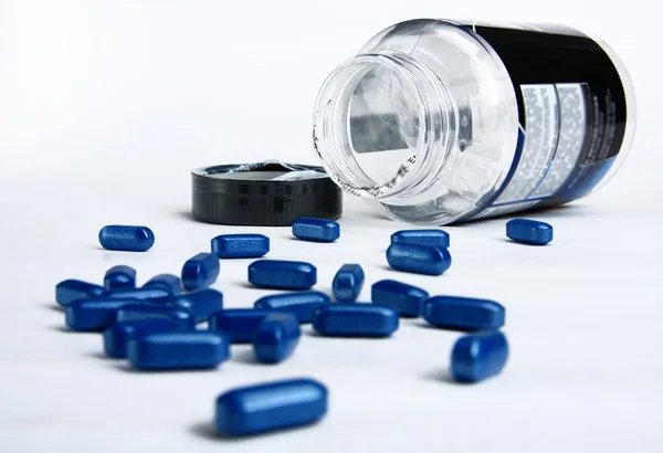 Pílulas azuis derramando fora da garrafa pílula — Fotografia de Stock