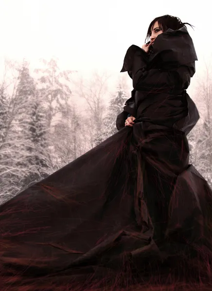 Girl in a long black dress on snow. — Stock Photo, Image