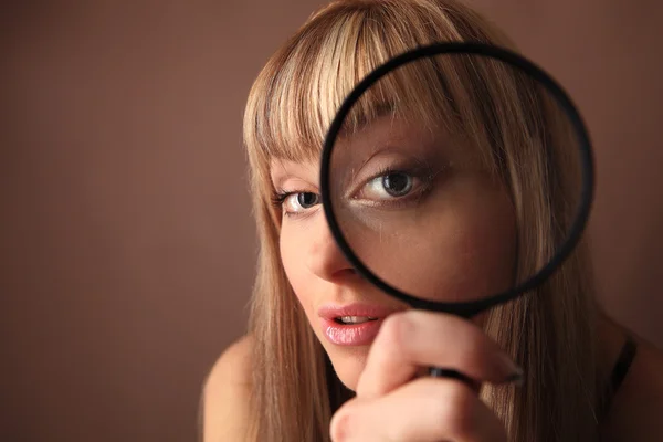 Attraente giovane ragazza guardando attraverso lente di ingrandimento — Foto Stock