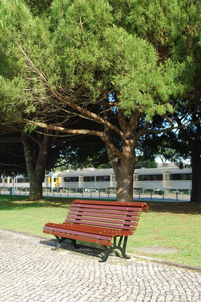 Ξύλινο πάγκο σε ένα πάρκο και ένα τρένο πρώτα — Φωτογραφία Αρχείου