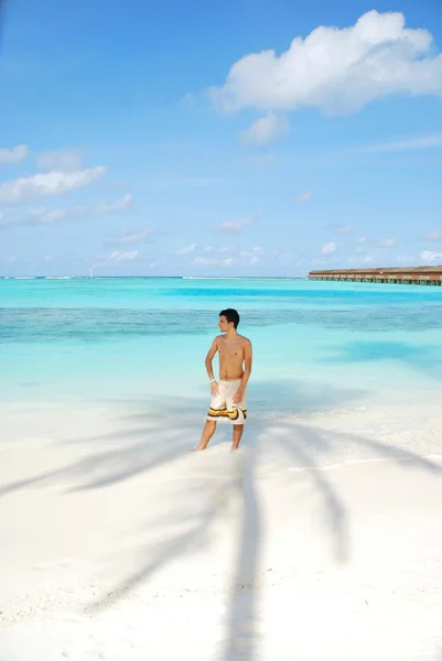 Young man standing on a tropical beach i — Stock Photo, Image