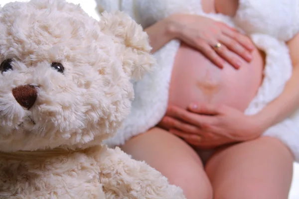 Mujer embarazada y oso de peluche Imagen de archivo