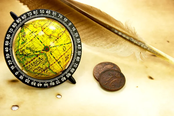 Old globe, feather and coins — Stock Photo, Image