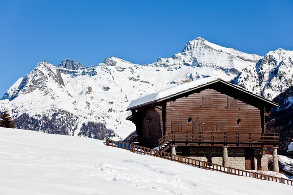 雪が降った山の向こうの木造コテージ — ストック写真