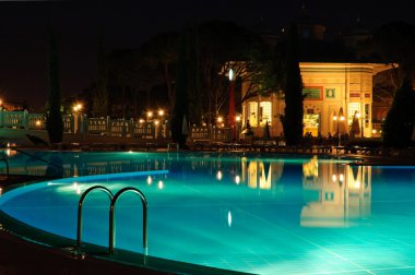 Swimming pool area in night illumination clipart