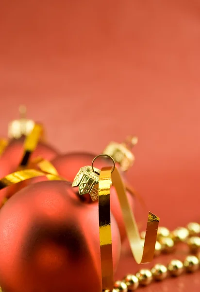 Три рождественские игрушки на красном фоне — стоковое фото