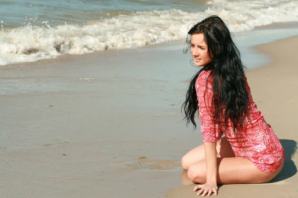 En vacker flicka sitter på stranden — Stockfoto