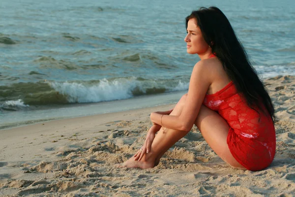 A beautiful girl is sitting on the beach — Stock Photo, Image