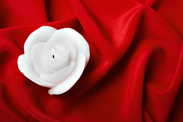 Świeczka Rose przeciwko czerwony jedwab — Zdjęcie stockowe