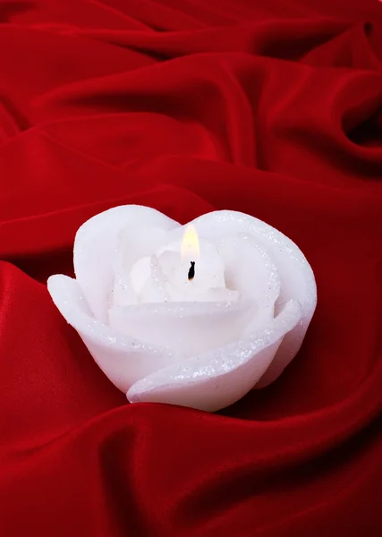 Kerze als Rose gegen rote Seide — Stockfoto