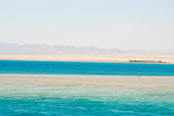 Одинокий человек, гуляющий по песчаному пляжу — стоковое фото