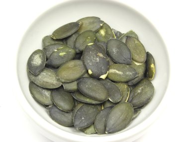 Pumpkin seeds in bowl of chinaware on wh