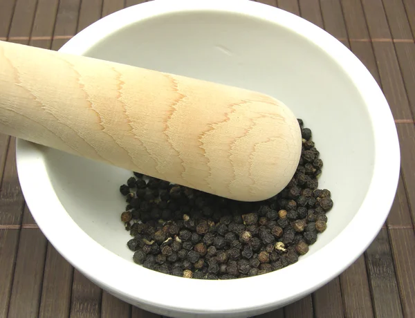 Pestling черный перец в миске — стоковое фото