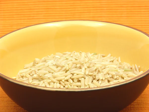 Brown rice in a bowl of ceramic on an or — Stock Photo, Image