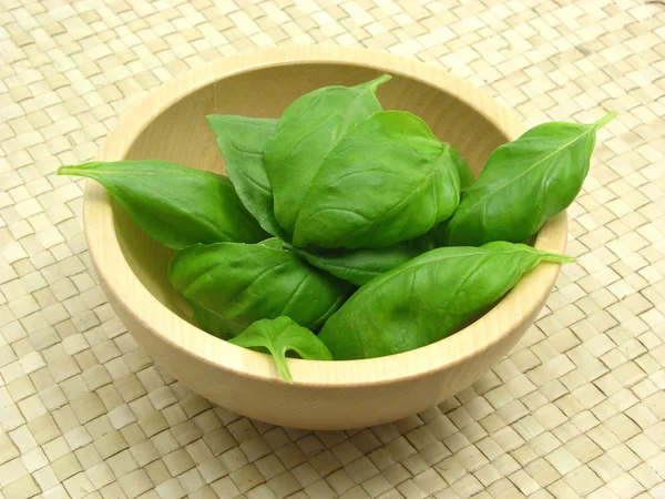 Wooden bowl with basil on rattan underla — Stock Photo, Image