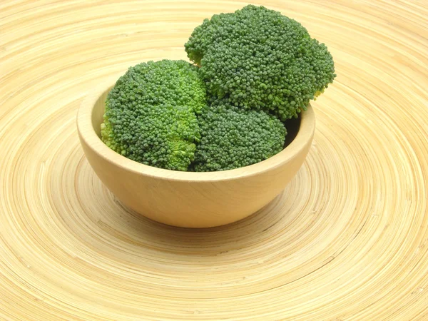 Wooden bowl with broccoli on bamboo plat — Stock Photo, Image