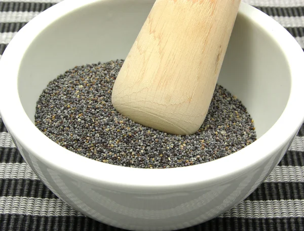 Pestling poppy seeds in a bowl of china — Stock Photo, Image