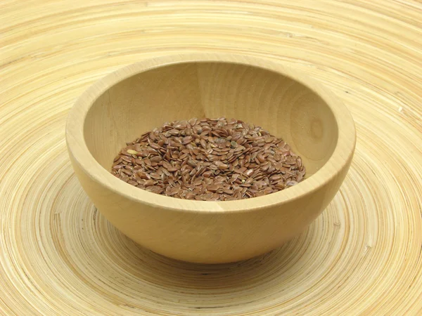 Wooden bowl with flaxseed on bamboo plat — Stock Photo, Image
