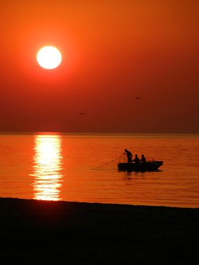 Fishing boat at sunset clipart