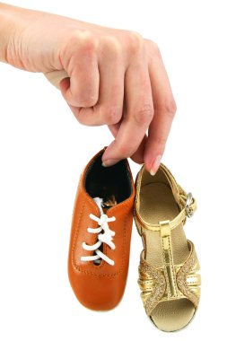 Female hand holds tiny dancing shoes clipart