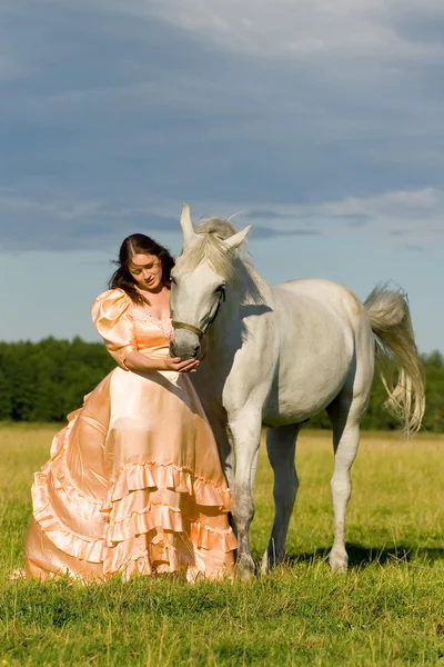 Jong meisje in jurk met grijze paard — Stockfoto