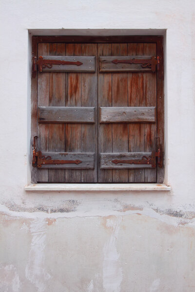 The closed old shutters against a white wall