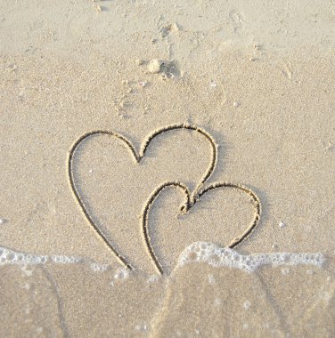 İki bağlı kalp ıslak kum üzerine çizilmiş