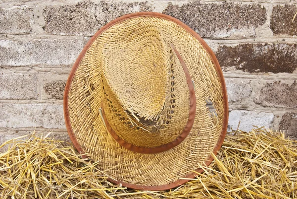 Vecchio cappello di paglia contro un muro di mattoni — Foto Stock