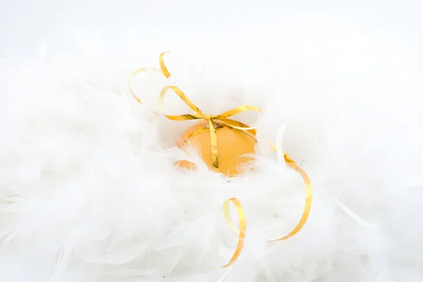 Naranja con una cinta entre plumas blancas — Foto de Stock