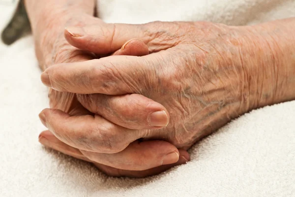 Old hands clasped on knees — Stock Photo, Image