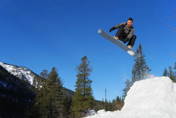 Gray snowboarder jumping high in the air — Zdjęcie stockowe