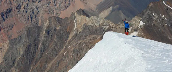 Альпинист, стоящий на вершине горы — стоковое фото