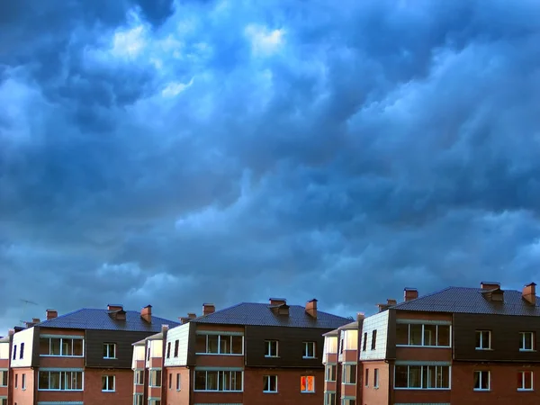 Дома против темных облаков — стоковое фото