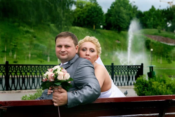 Newly-married couple sitting on a bench — Stock Photo, Image
