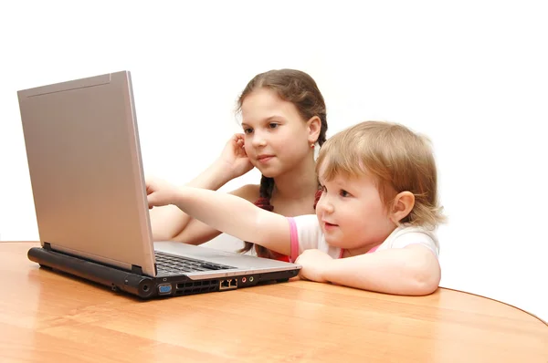 在笔记本电脑后面的两个小女孩 — 图库照片