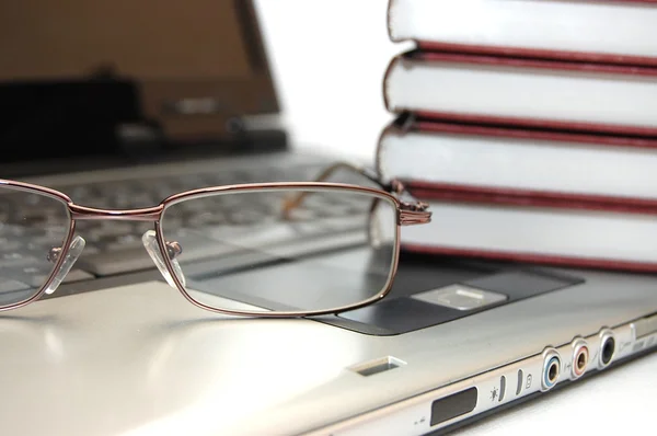 Brillen en boeken over de laptop — Stockfoto