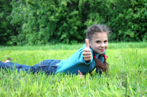 Girl with thumb on a green grass — Stock Photo, Image