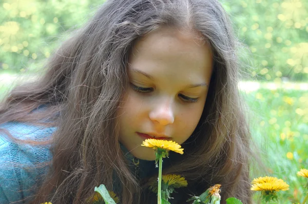 Девочка смотрит на цветок одуванчика — стоковое фото
