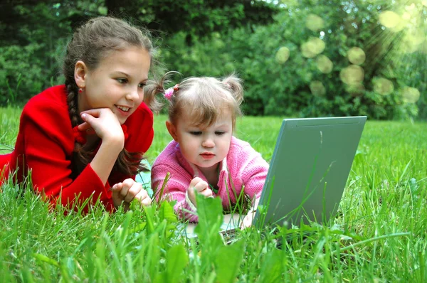 Happy sisters with laptop on the meadow — Stock Photo, Image