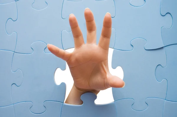 Mão feminina através de um puzzle — Fotografia de Stock