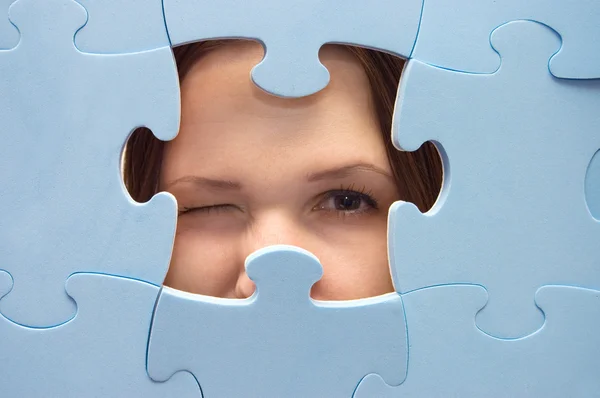 The girl spies through a blue puzzle — Stock Photo, Image