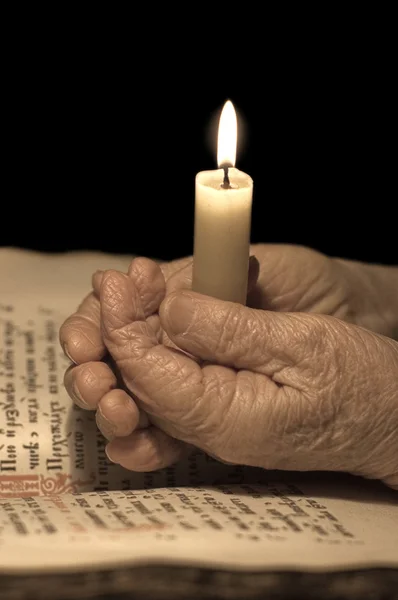 Vecchie mani femminili con una candela — Foto Stock